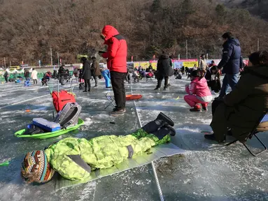 Peserta memancing ikan trout melalui lubang yang mereka buat di atas sungai beku di Hwacheon, Korea Selatan, Sabtu (5/1). Kontes ini merupakan bagian dari festival es tahunan yang menarik lebih dari satu juta pengunjung setiap tahun. (AP/Ahn Young-joon)