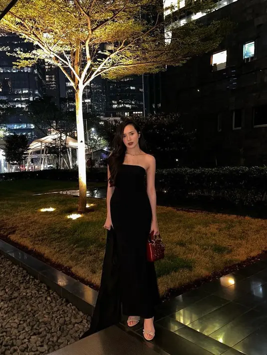 Beby tampak elegan dengan dress hitam panjang tube dipadukan heels strap sambil membawa tas merah Dior.  [@bebytsabina]