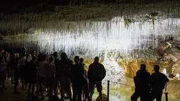 Pengunjung melihat es di dalam gua alam Choranche, di wilayah Vercors dekat Grenoble, Prancis (3/8). Sejak dimulainya gelombang panas, telah terjadi peningkatan setidaknya 10 persen jumlah pengunjung gua. (AFP Photo/Jean-Pierre Clatot)