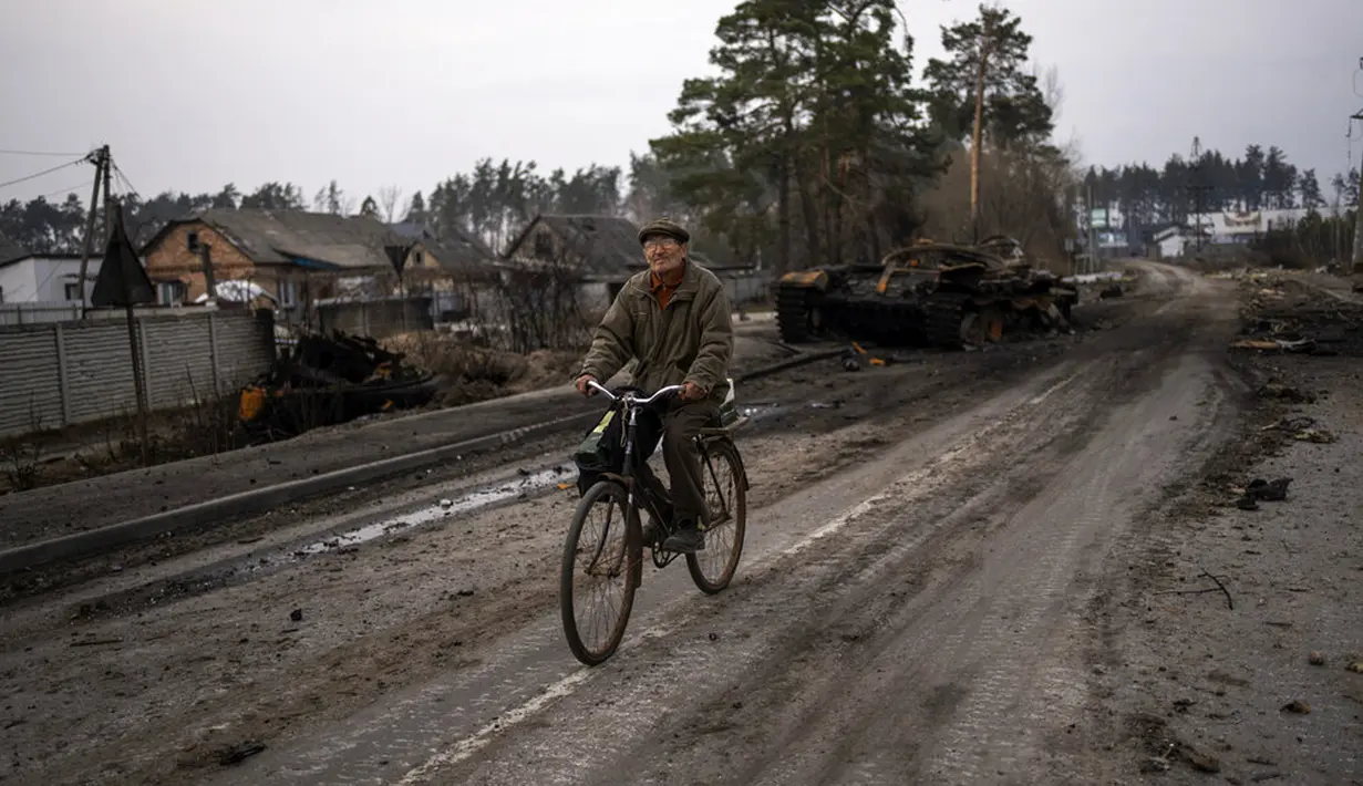 Oleksandr (81) mengendarai sepeda dekat tank Rusia yang hancur di pinggiran Kiev, Ukraina, 31 Maret 2022. Pasukan Rusia menembaki pinggiran Kota Kiev, dua hari setelah Kremlin mengumumkan akan secara signifikan mengurangi operasi dekat Ibu Kota dan Chernihiv. (AP Photo/Rodrigo Abd)