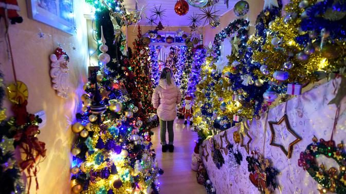 Seorang gadis berdiri di antara pohon-pohon Natal yang menghiasi rumah keluarga Thomas Jeromin di Rinteln, Jerman, 8 Desember 2019. Thomas Jeromin memenuhi rumahnya dengan 350 pohon Natal di hampir tiap sudut rumah, mulai dari ruang tamu, dapur sampai kamar mandi. (Ina FASSBENDER/AFP)