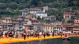 Sejumlah wisatawan berjalan di atas instalasi "The Floating Piers" karya Christo Vladimirov Javacheff di Danau Iseo, Italia, (24/6). Proyek seni instalasi ini telah menghabiskan biaya USD 16,7 juta atau sekitar Rp 224 miliar. (REUTERS/Stefano Rellandini)