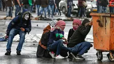 Wanita Palestina bersembunyi di balik tong selama bentrokan dengan tentara Israel dalam demonstrasi untuk memperingati Hari Tanah di Tepi Barat, Sabtu (30/3). (Photo by ABBAS MOMANI/AFP)