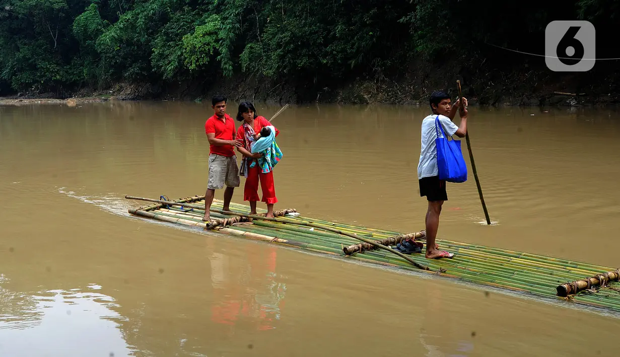 Warga menyeberangi Sungai Cikaniki dengan rakit di Rumpin, Bogor, Jawa Barat, Rabu (15/1/2020). Akibat banjir bandang merobohkan jembatan yang menghubungkan Desa Tonjong Rumpin dan Desa Kantalarang Leuwiliang, warga terpaksa memanfaatkan perahu rakit untuk melintas. (merdeka.com/Arie Basuki)