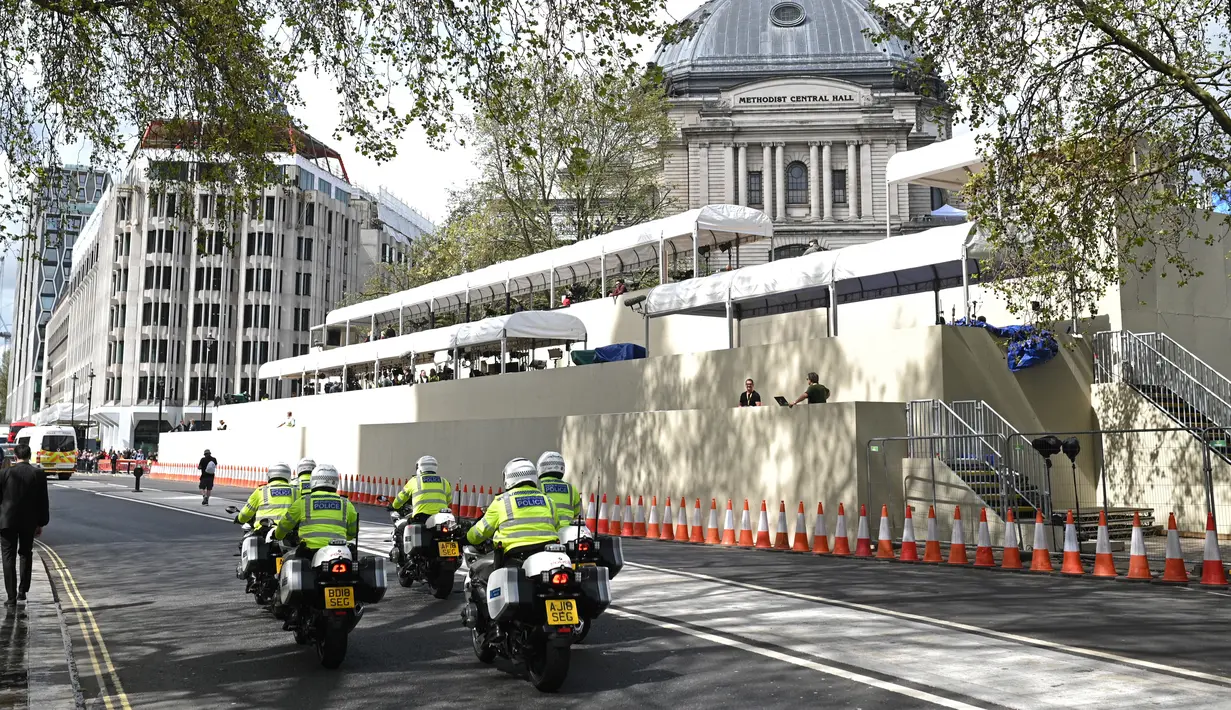 Patroli polisi bermotor melewati stan media, yang didirikan di luar Westminster Abbey menjelang akhir pekan penobatan Raja Charles III dan Ratu Camilla  di pusat kota London, Jumat (5/5/2023). (Photo by Oli SCARFF / AFP)