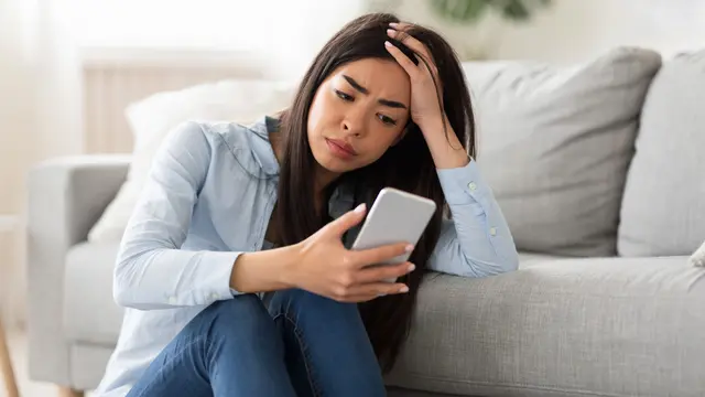 perempuan stres memegang ponsel