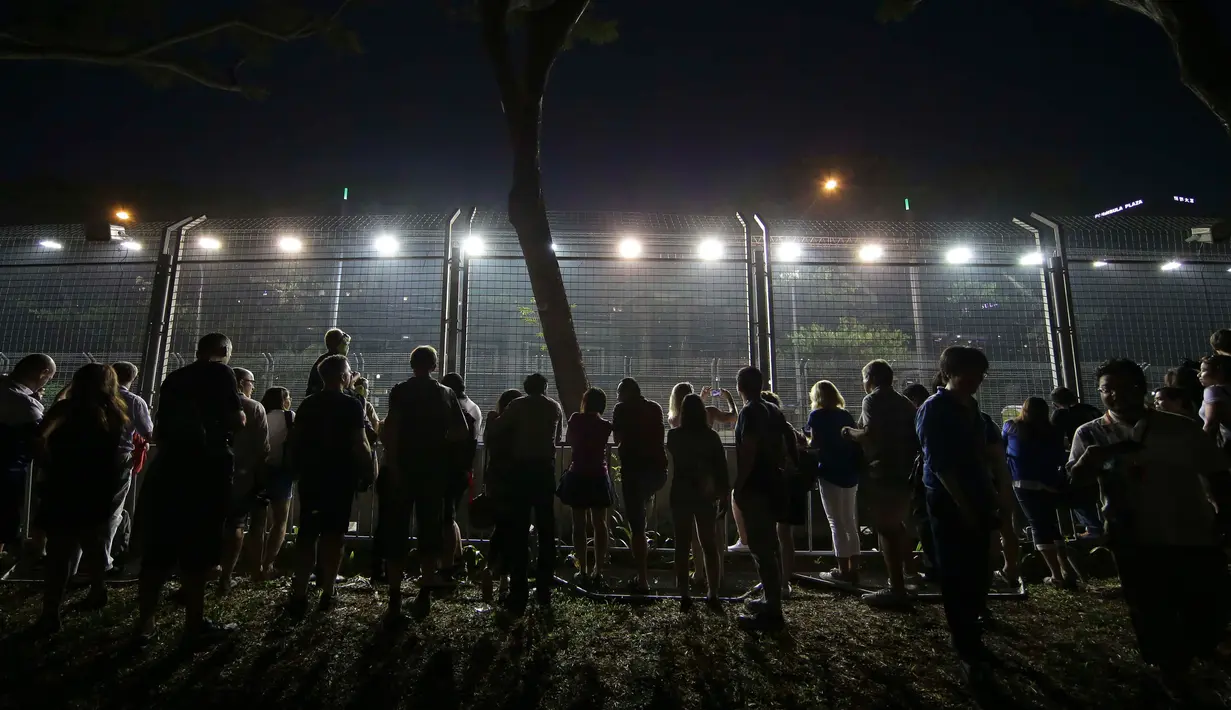Penonton menyaksikan dari luar sirkuti saat sesi latihan Grand Prix Singapura F1 (18/9/2015). Kabut asap yang menyelimuti sirkuit tak menyurutkan pembalap untuk tetap melakukan pemanasan. (Singapore Grand Prix /Reuters)