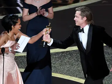 Regina King memberikan piala Oscar kepada Brad Pitt di atas panggung ajang Academy Awards ke-92 di Dolby Theatre, Los Angeles, Minggu (9/2/2020). Brad Pitt menyabet penghargaan sebagai Aktor Pendukung Terbaik untuk aktingnya di film Once Upon a Time in Hollywood. (Kevin Winter/Getty Images/AFP)