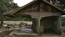 Seorang warga desa melihat-lihat dari rumahnya yang rusak akibat banjir bandang di Garoga, Provinsi Sumatera Utara, pada Kamis 4 Desember 2025. (YT HARIONO/AFP)