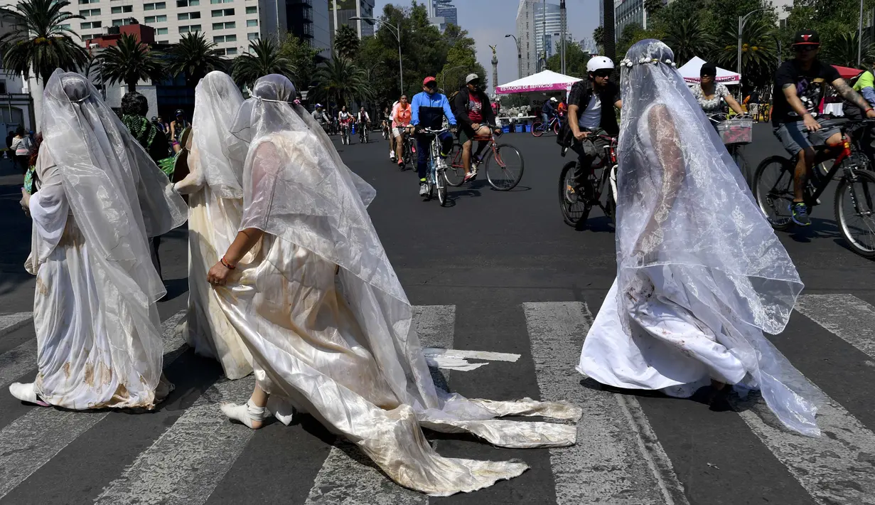 Sejumlah wanita mengenakan gaun dan kerudung putih  dengan noda darah melintas di jalan Mexico City, Meksiko (7/5). Mereka mengenakan pakaian tersebut untuk menggelar aksi "Las 43 Lloronas". (AFP Photo/Yuri Cortez)