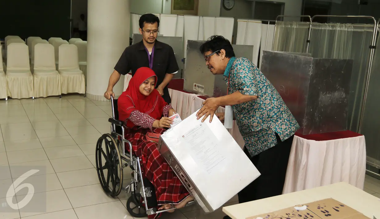 Pasein RSCM Hikna Solehah dibantu petugas memasukan surat suara saat mengikuti Pilkada DKI 2017 di TPS 15 RSCM, Jakarta, Rabu (15/2/2017). (Liputan6.com/Herman Zakharia)