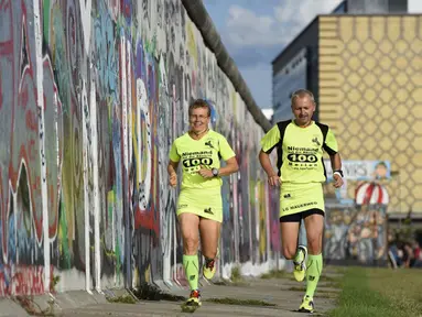 Martina Schliep (kiri) dan Gaston Pruefer berlari di sisi timur Tembok Berlin, Jerman, (11/8/2014). (AFP PHOTO/Tobias Schwarz)