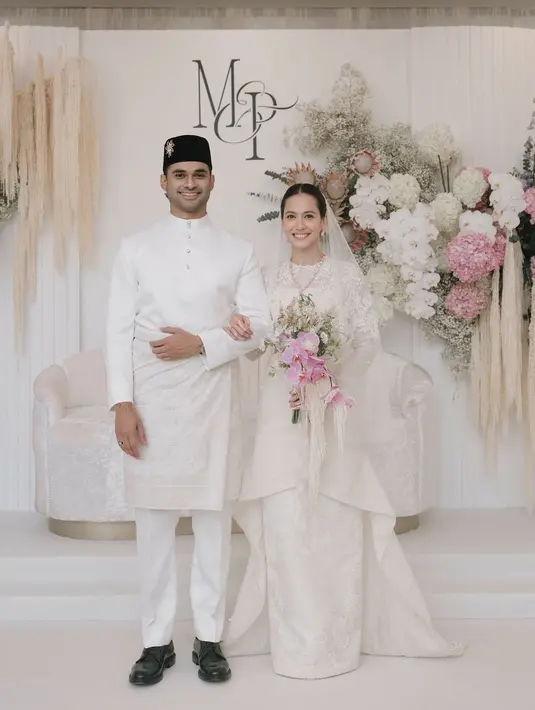 Sekilas tampak sederhana, baju kurung Pevita memiliki detail yang unik. Terdapat ekor panjang ke belakang yang menambah impresi elegan. Dipadukan dengan rok panjang dengan aksen bordiran. Suaminya, mengenakan atasan putih lengan panjang berkancing dipadukan songket di atas celana panjangnya. Lengkap mengenakan peci hitam dengan bros emas.