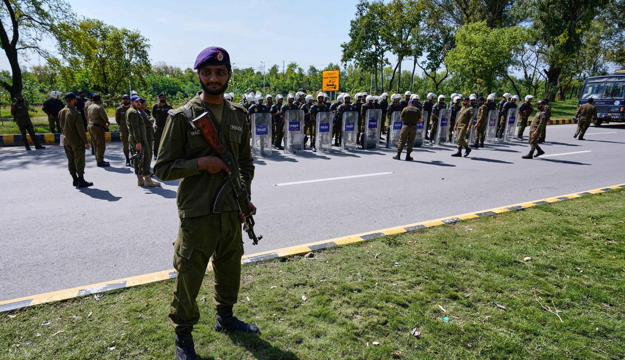 Sejumlah personel militer dan polisi Pakistan bersenjata lengkap menjaga seluruh ruas jalan, terutama yang menuju lokasi perundingan. Tampak dalam foto, seorang petugas polisi berjaga sementara yang lain mengikuti pengarahan sebelum penugasan mereka untuk memastikan keamanan menjelang kemungkinan negosiasi antara Amerika Serikat dan Iran di ibu kota Pakistan, Islamabad, Jumat 10 April 2026. (AP Photo/Anjum Naveed)