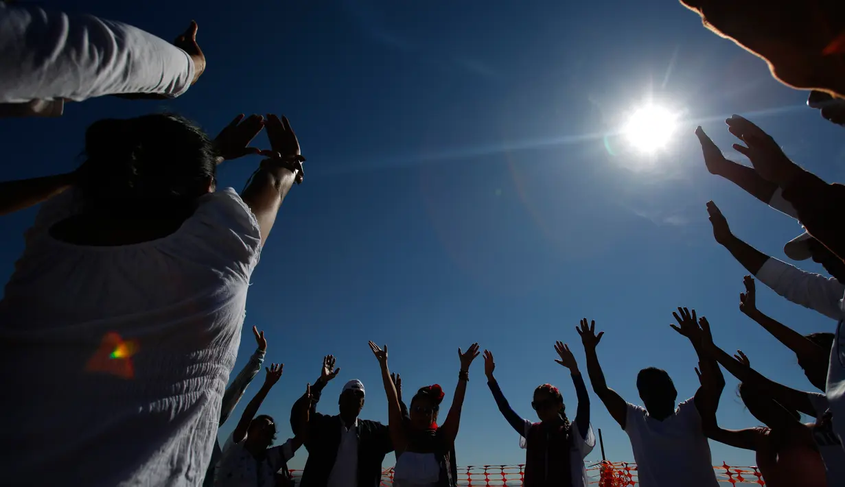 Pengunjung mengangkat tangan mereka untuk menerima energi matahari saat equinox musim semi di situs arkeologi Teotihuacan, Meksiko (21/3). Ritual ini dipercaya bisa mengalirkan energi positif serta mengusir roh jahat. (AP Photo/Rebecca Blackwell)