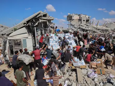 Penduduk Palestina berkumpul di sekitar truk bantuan yang masuk melalui pos perbatasan Karem Abu Salem di Khan Yunis, bagian selatan Jalur Gaza, pada 12 Oktober 2025. (Omar AL-QATTAA/AFP)