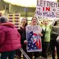 Calon penumpang melewati massa yang menggelar aksi protes di Terminal Internasional Tom Bradley, Bandara LAX, Los Angeles, Sabtu (28/1). Mereka menggelar aksi protes terkait kebijakan Presiden AS Donald Trump tentang imigrasi. (AP Photo/Reed Saxon)