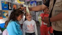 Untuk diketahui, di Gaza, burung sering menjadi simbol harapan dan ketahanan dalam karya seni lokal. Tampak dalam foto, anak-anak pengungsi Palestina mengikuti sesi konseling psikologis di sebuah studio seni yang menggunakan hewan peliharaan dan burung di daerah Al-Zawaida, Jalur Gaza Tengah, pada Selasa 21 April 2026. (Eyad Baba/AFP)