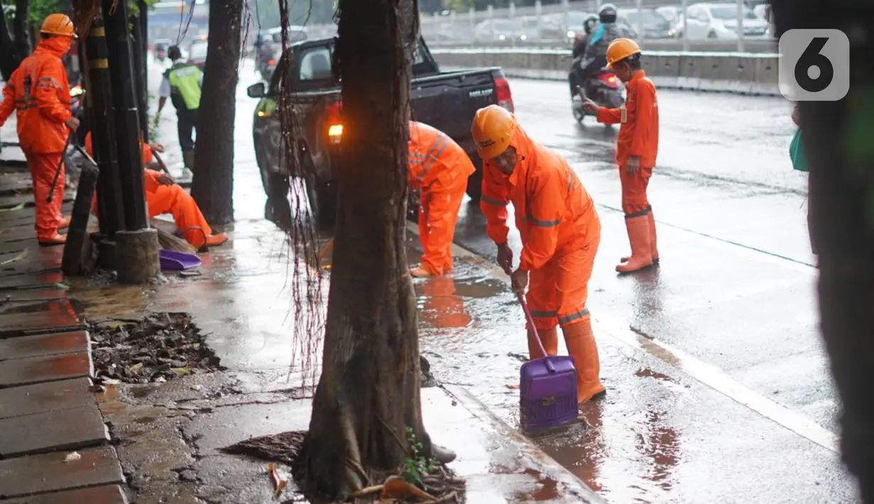 Petugas PPSU membersihkan saluran air yang tersumbat di Jalan Mampang Prapatan Raya, Jakarta, Rabu (11/12/2019). Hal tersebut dilakukan guna mengurangi genangan air yang terjadi di sejumlah sudut Ibukota setiap kali hujan deras mengguyur Jakarta. (Liputan6.com/Immanuel Antonius)