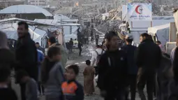 Upaya pemulihan yang signifikan belum dapat dilakukan secara efektif di tengah situasi keamanan yang masih bergejolak. Tampak dalam foto, pengungsi Palestina berjalan melalui jalan berlumpur di antara tenda-tenda yang didirikan di antara bangunan-bangunan yang hancur di Jabalia, di bagian utara Jalur Gaza, Minggu 7 Desember 2025. (AP Photo/Jehad Alshrafi)