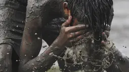 Seorang anak mencuci mukanya saat bermain permainan Kabaddi di sebuah lahan yang digenangi air di Kolkata (8/9/2019). Olahraga ini merupakan olahraga nasional Bangladesh, dan olahraga negara bagian Punjab, Tamil Nadu dan Andhra Pradesh di India. (AFP Photo/Dibyangshu Sarkar)