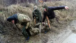 Warga sipil melakukan penyelamatan prajurit yang terluka saat mengikuti sesi pelatihan militer oleh Right Sector dekat Lviv, Ukraina, 24 Februari 2023. (AP Photo/Mykola Tys)