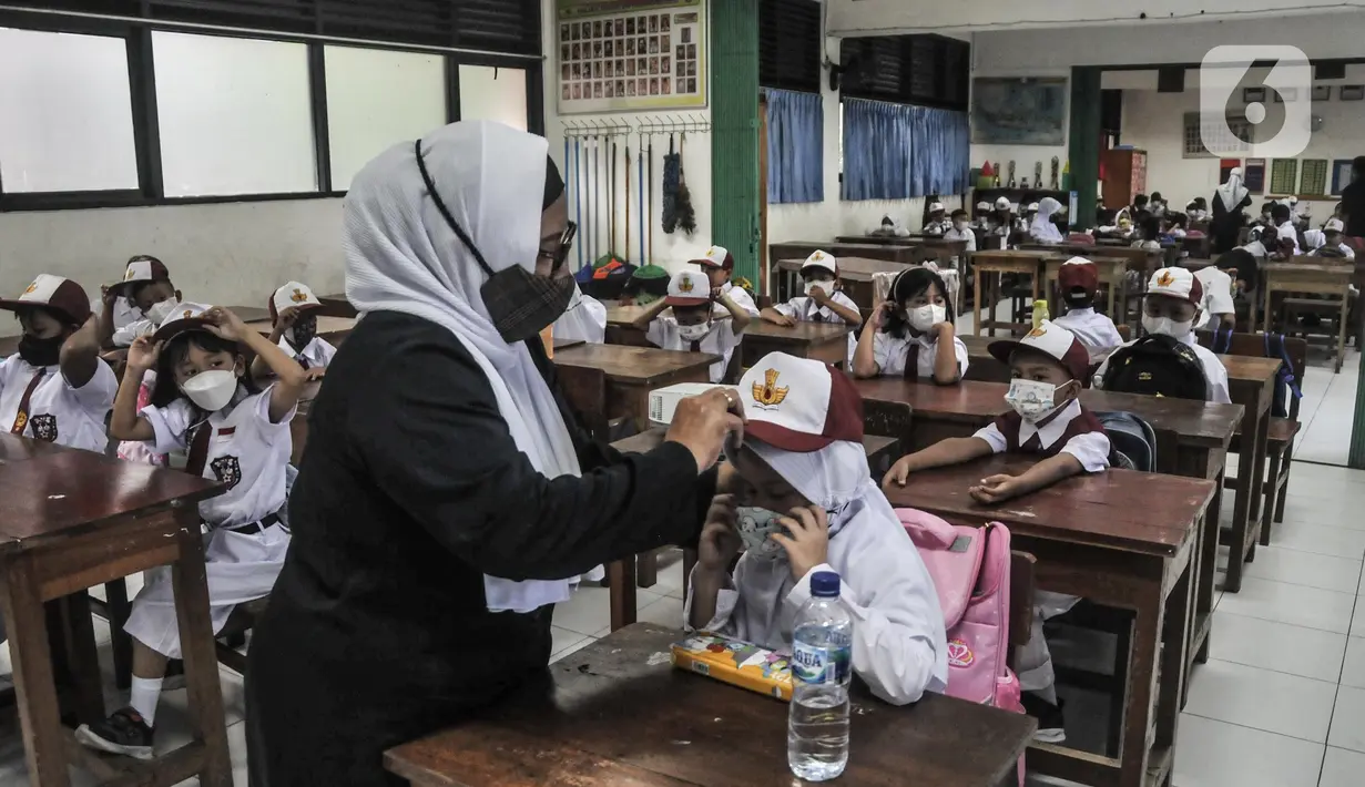 Guru membimbing murid kelas 1 saat Masa Pengenalan Lingkungan Sekolah (MPLS) di Sekolah Dasar (SD) Negeri Jati 06 Pagi, Pulogadung, Jakarta Timur, Senin (11/7/2022). PTM 100 persen tetap disiplin menerapkan protokol kesehatan guna mencegah penyebaran Covid-19 di lingkungan sekolah. (merdeka.com/Iqbal S. Nugroho)