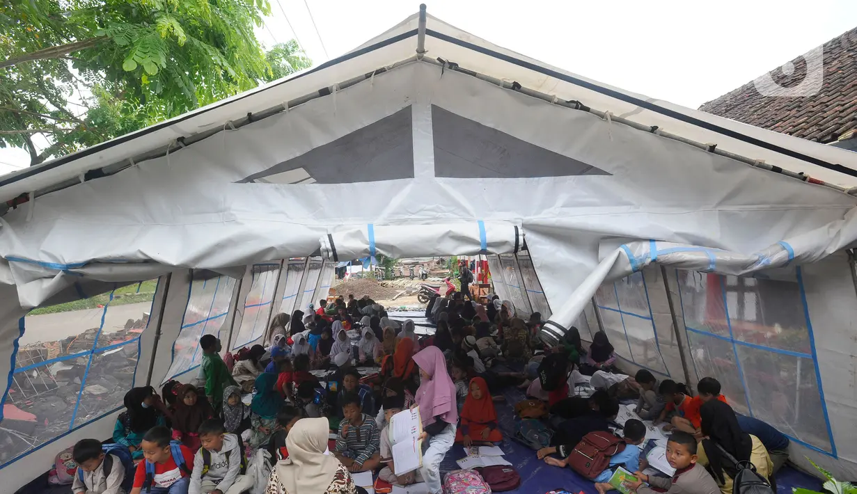 Murid-murid korban gempa belajar pada tenda darurat yang dibangun di halaman sekolah di SDN Gintung, Mangunkerta, Cianjur, Jumat (23/12/2022). Lebih dari sebulan sejak musibah gempa bumi 5,2 SR sejumlah murid sekolah di Cianjur masih belajar pada tenda darurat. (merdeka.com/Arie Basuki)