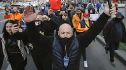 Warga yang memprotes pembatasan terkait pandemi COVID-19 berbaris di pusat Kota Bucharest, Rumania, Senin (29/3/2021). Ribuan pengunjuk rasa antipembatasan turun ke jalan di beberapa kota Rumania sehari setelah langkah pembatasan baru diberlakukan. (AP Photo/Vadim Ghirda)