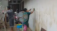 Warga Rawajati membersihkan rumah setelah terendam banjir. (Merdeka.com)