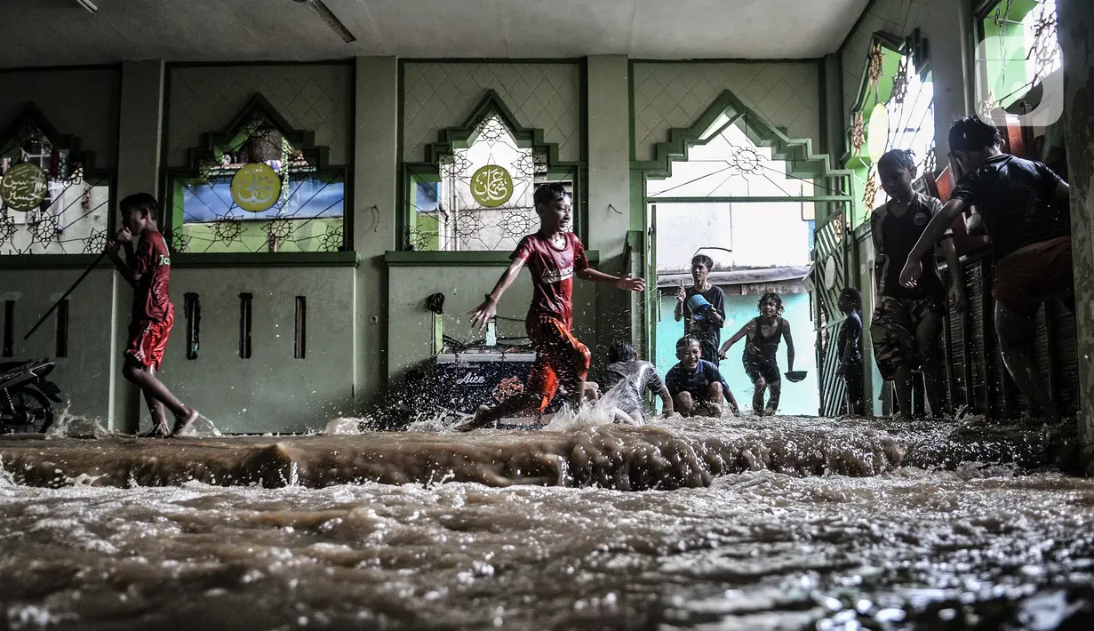 Anak-anak bermain air yang merendam sebuah masjid di Kebon Pala, Jakarta, Senin (8/2/2021). Hujan deras yang mengguyur Ibu Kota dan wilayah Bogor menyebabkan permukiman di Kebon Pala terendam banjir sejak Minggu (7/2/2021) sore. (merdeka.com/Iqbal S. Nugroho)