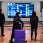 Penumpang berjalan melalui aula kedatangan di Bandara Internasional Haneda Tokyo, Jumat (18/2/2022). Pemerintah Jepang mengumumkan rencana untuk melonggarkan aturan perbatasan virus bagi pekerja dan pelajar. (AFP/Philip Fong)