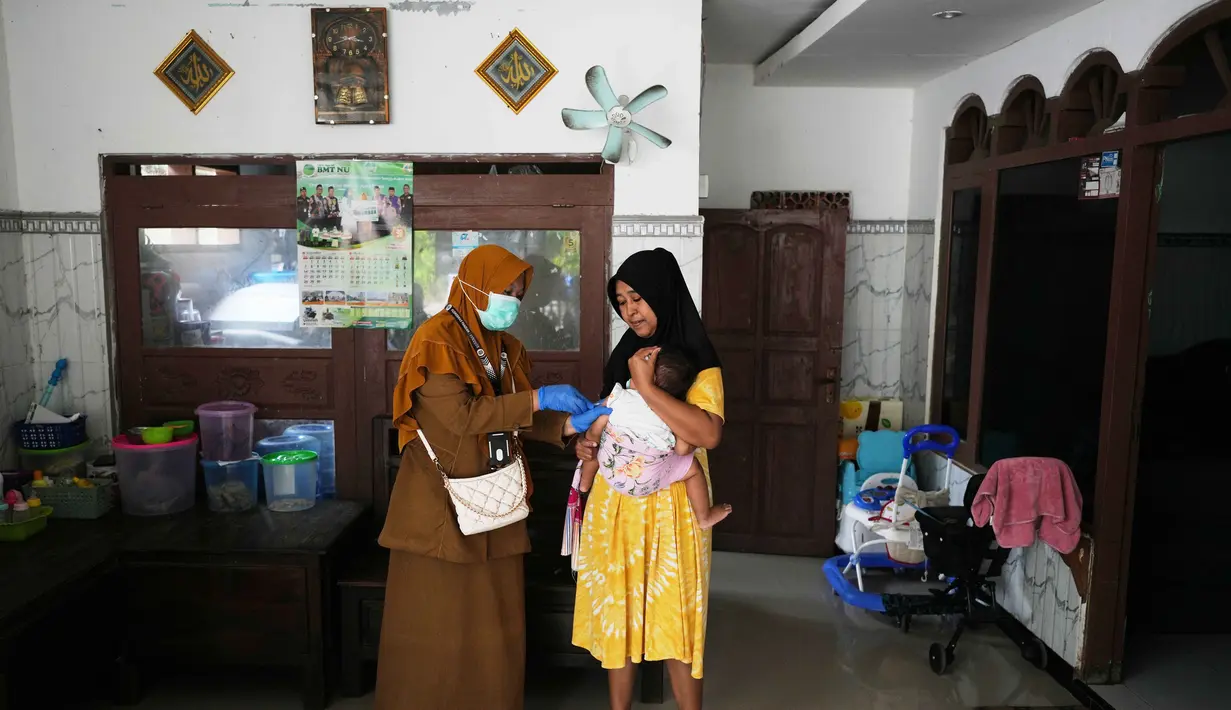 Tenaga kesehatan Siti Nurjanah memberikan vaksinasi campak dalam kampanye dari rumah ke rumah menyusul wabah di Sumenep, Pulau Madura, Jawa Timur, Senin 8 September 2025. (AP Photo/Dita Alangkara)