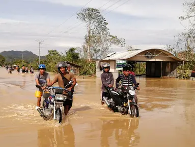 Pengendara sepeda motor melintasi jalan raya yang banjir usai terjangan topan Phanfone di Ormoc City, Provinsi Leyte, Filipina, Rabu (25/12/2019). Topan membuat jutaan warga di negara yang mayoritas beragama Katolik itu merayakan Natal dengan kesedihan. (RONALD FRANK DEJON/AFP)