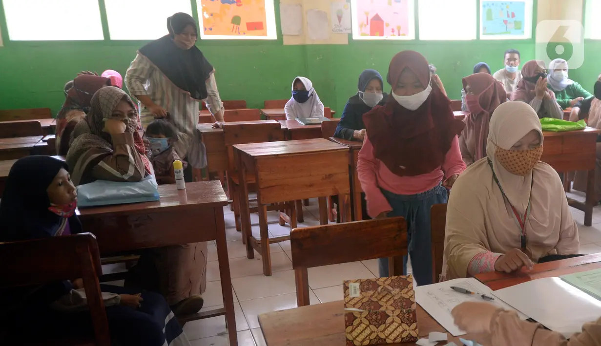 Siswa Sekolah SD kelas 4,5 dan 6 didampingi wali murid sedang mengambil rapot secara bergilir di Sekolah Islam Raudlatul Hikmah, Parakan, Pondok Benda, Pamulang, Tangerang Selatan, Banten, Jumat (16/10/2020).  (merdeka.com/Dwi Narwoko)