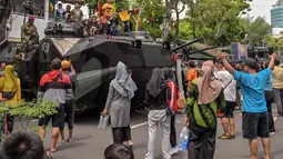 Menandai peringatan Hari Ulang Tahun ke-80, Korps Marinir TNI AL menggelar pameran alat utama sistem senjata atau alat utama sistem pertahanan (Alutsista) serta sejumlah kegiatan lainnya di sekitaran Gedung Negara Grahadi, Surabaya, Jawa Timur. Tampak dalam foto, warga berfoto bersama kendaraan militer selama Pameran Marinir Indonesia, yang menandai peringatan Hari Ulang Tahun ke-80 Korps Marinir TNI AL di Surabaya, Jawa Timur pada Minggu 9 November 2025. (JUNI KRISWANTO/AFP)