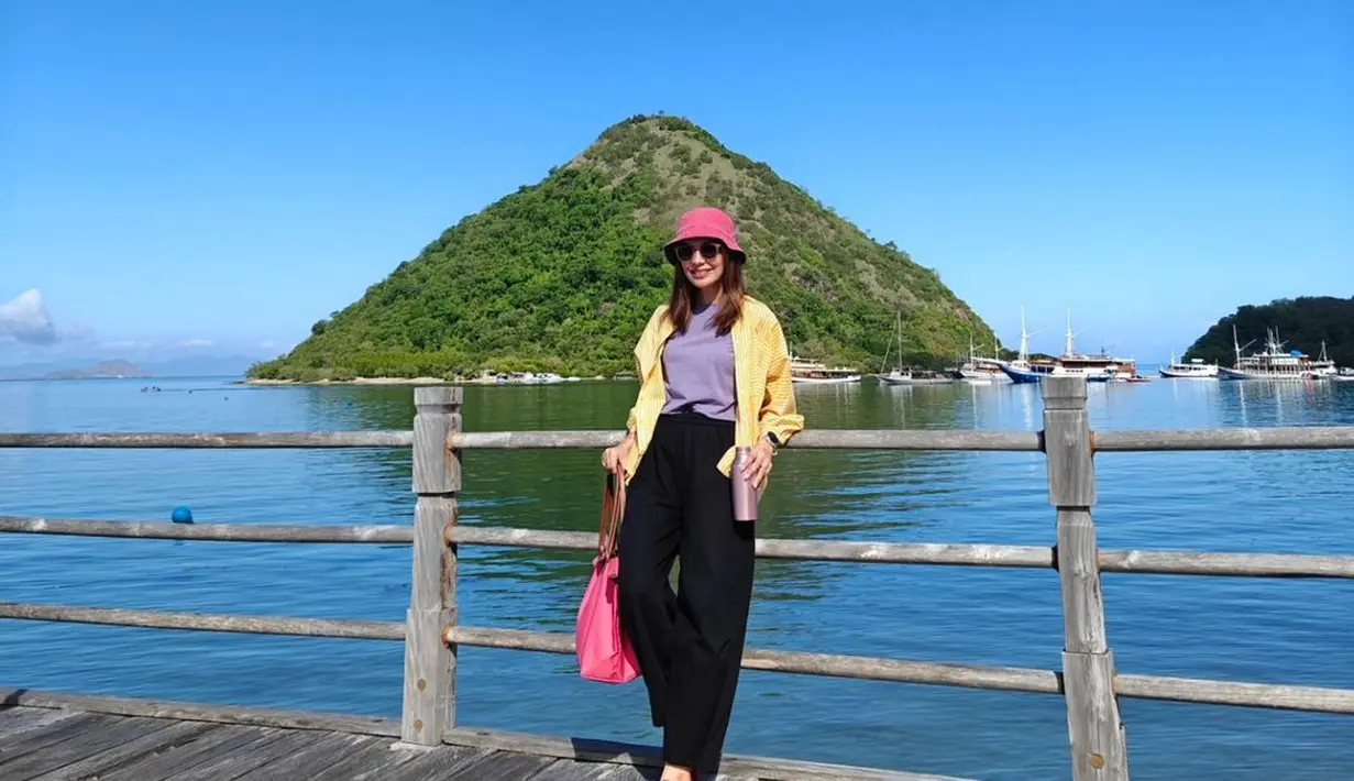 Ia mengenakan t-shirt ungu dipadukan dengan kemeja stripe kuning dan celana hitam. Flatshoes merah dan bucket pink jadi sentuhan manis. [@najwashihab]