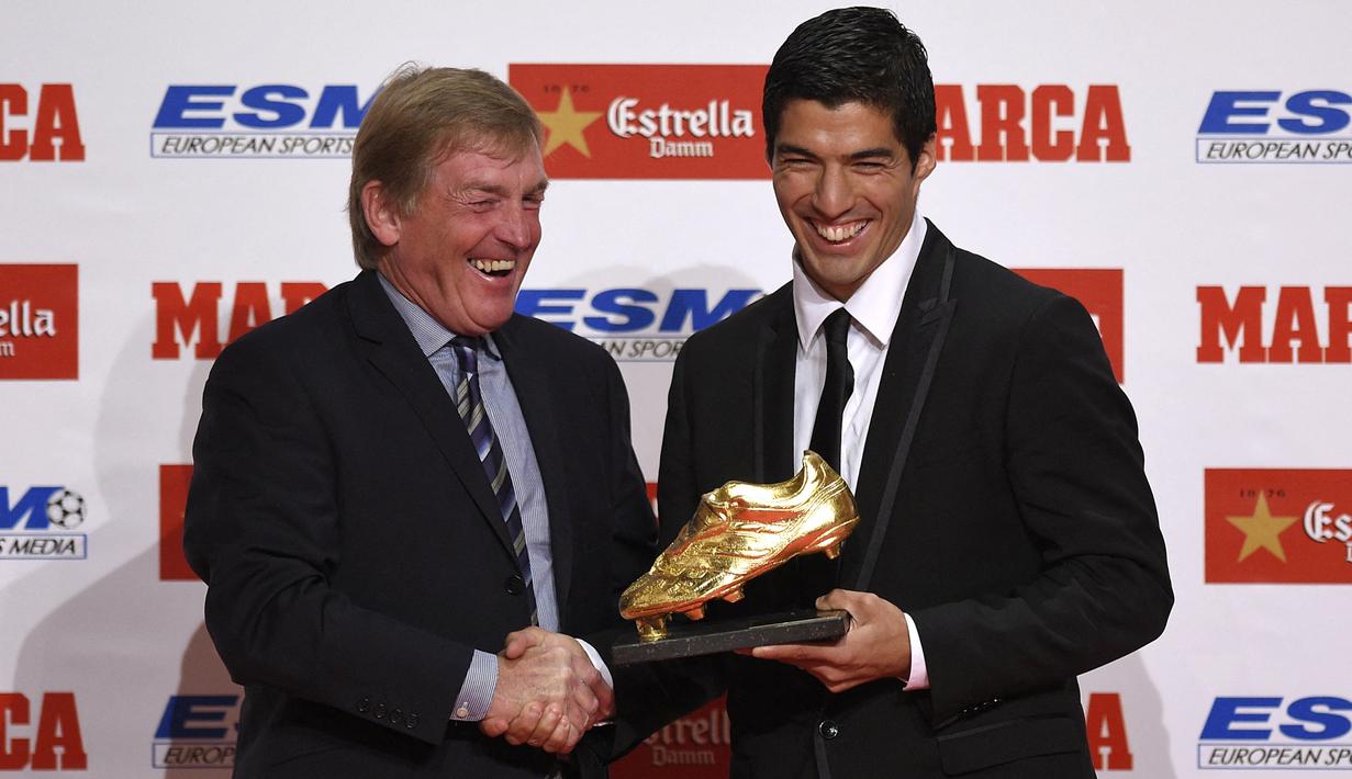 Eks pemain Liverpool, Kenny Dalglish (kiri) menyalami striker Barcelona, Luis Suarez yang meraih trofi Sepatu Emas Eropa saat membela Liverpool, di Barcelona (15/10/2014). Luis Suarez merebut trofi Sepatu Emas Eropa edisi 2014 setelah mencetak total 31 gol bagi Liverpool di Liga Inggris musim 2013/2014, bersanding dengan Cristiano Ronaldo (Real Madrid). Setelah hijrah ke Barcelona pada 2014/2015, Luis Suarez merebut Sepatu Emas Eropa pada musim 2015/2016. (AFP/Lluis Gene)