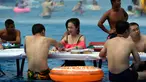 Sejumlah orang bermain catur di dalam kolam renang saat cuaca panas melanda wilayah Chongqing di Tiongkok, Rabu (2/8). Tiongkok saat ini dilaporkan sedang mengalami cuaca panas dengan suhu di beberapa daerah hampir mencapai 40 derajat celcius. (STR / AFP)