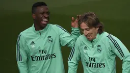 Striker Real Madrid, Vinicius Junior (kiri) dan gelandang Luka Modric tertawa saat menghadiri sesi pelatihan di tempat latihan tim Valdebebas, Spanyol (5/11/2019). Real Madrid akan melawan Galatasaray pada Grup A Liga Champions di Estadio Santiago Bernabeu. (AFP Photo/Pierre-Philippe Marcou)