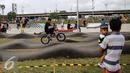 Seorang ayah yang menggendong anak menonton aksi pesepeda BMX Taman Kalijodo, Jakarta, Minggu (15/01). Sejak skate park dan lintasan sepeda BMX dibuka untuk umum, taman tersebut tidak pernah sepi pengunjung. (Liputan6.com/Fery Pradolo)