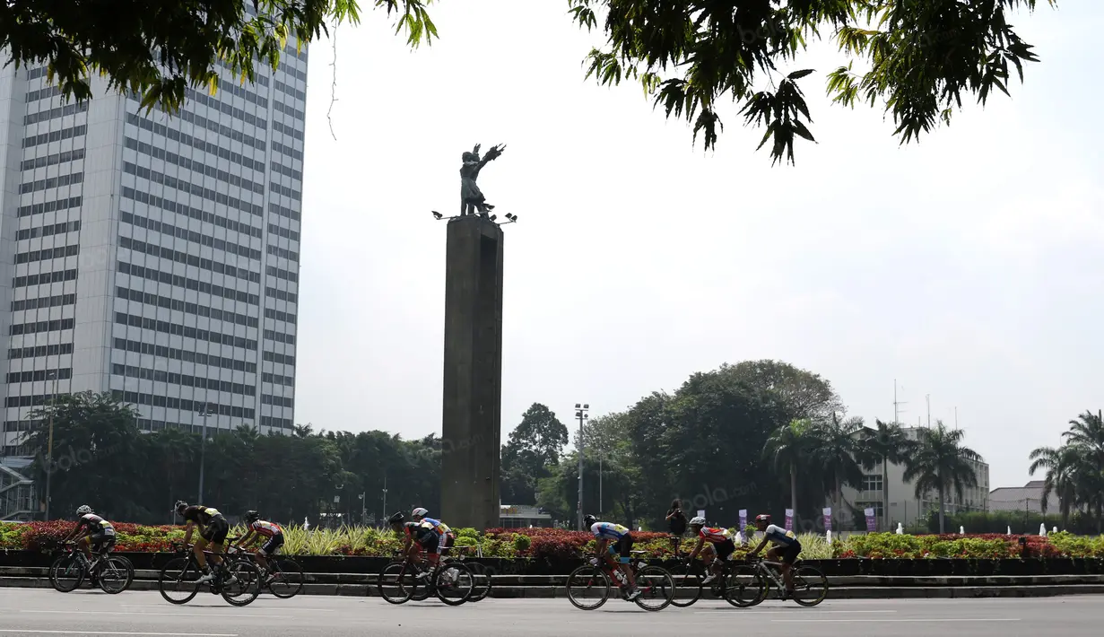 Para pebalap melewati patung Selamat Datang pada ajang Tour de Jakarta di Bundaran Hotel Indonesia, Jakarta, Sabtu (30/7/2016). (Bola.com/Nicklas Hanoatubun)