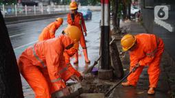 Petugas PPSU membersihkan saluran air yang tersumbat di Jalan Mampang Prapatan Raya, Jakarta, Rabu (11/12/2019). Hal tersebut dilakukan guna mengurangi genangan air yang terjadi di sejumlah sudut Ibukota setiap kali hujan deras mengguyur Jakarta. (Liputan6.com/Immanuel Antonius)