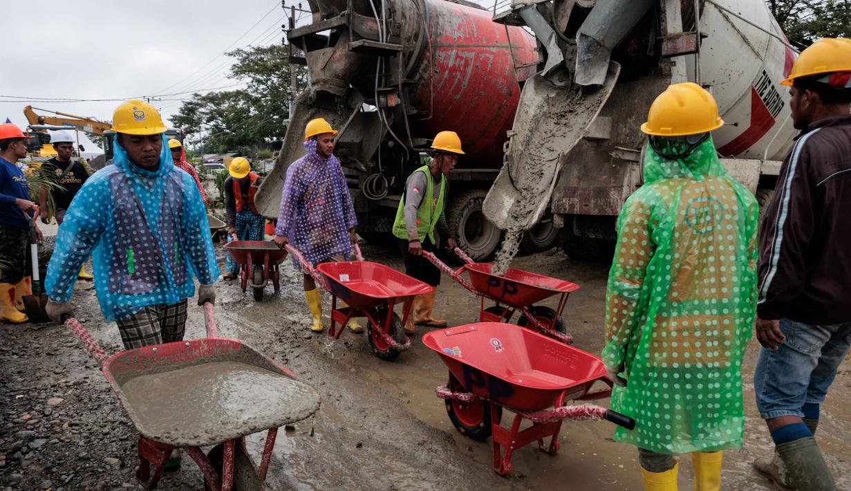 Sementara PTPP berperan dalam pelaksanaan pembangunan hunian secara cepat, terukur, dan sesuai standar keselamatan konstruksi. Tampak dalam foto, para pekerja mengangkut beton dengan gerobak dorong selama pembangunan unit perumahan sementara yang dibangun oleh Danantara, Badan Pengelola Investasi (BPI) strategis Indonesia, di Aceh Tamiang, provinsi Aceh, pada Kamis 8 Januari 2026. (ADITYA AJI/AFP)