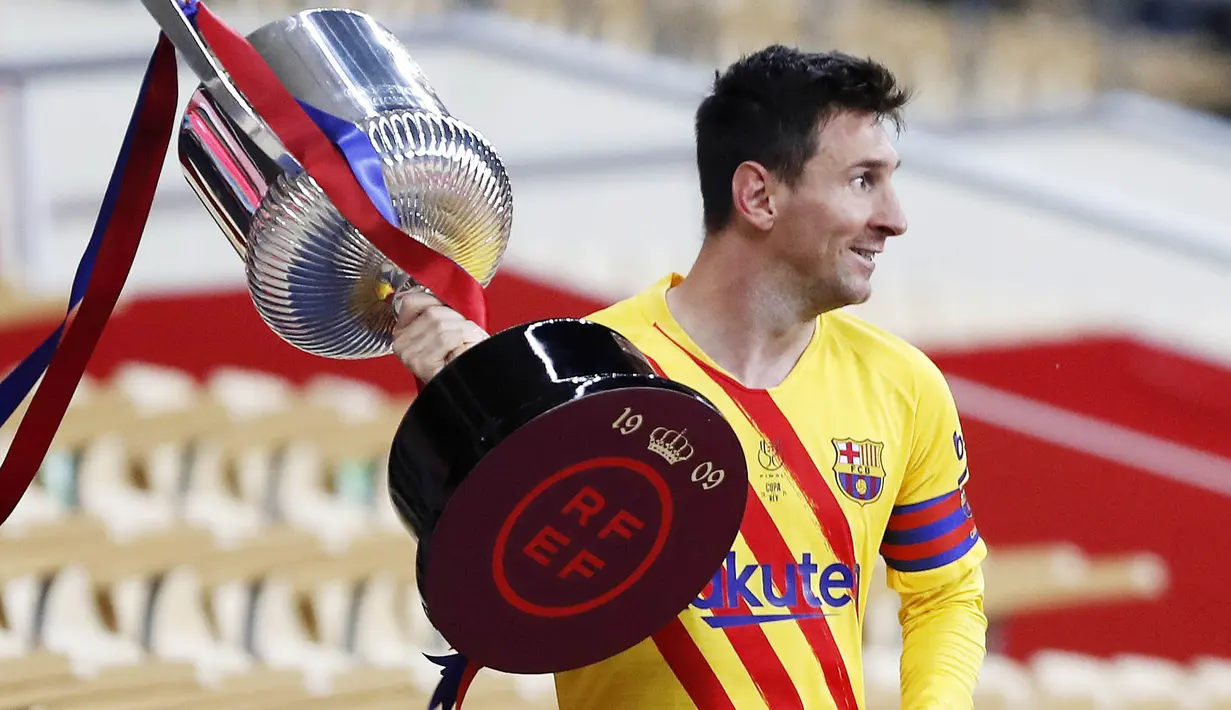 Striker Barcelona, Lionel Messi, mengangkat trofi usai menjuarai Copa del Rey di Stadion Olimpico de Sevilla, Minggu (18/4/2021). Barcelona menang 4-0 atas Athletic Bilbao. (AP/Angel Fernandez)