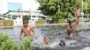 Anak-anak berenang di kolam air mancur penghias kawasan Pasar Baru, Jakarta, Selasa (29/1). Keterbatasan lahan bermain menyebabkan sebagian anak di Ibukota bermain tidak pada tempatnya, meskipun berbahaya bagi keselematan. (Liputan6.com/Immanuel Antonius)