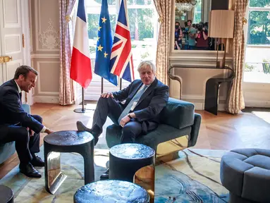 Perdana Menteri Inggris Boris Johnson menjadi sorotan setelah menaruh kaki di meja di depan Presiden Perancis Emmanuel Macron dalam kunjungan kenegaraan.(Christophe Petit Tesson, Pool via AP)