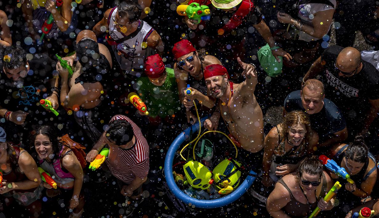 Orang-orang mengikuti perang air tahunan di jalan-jalan lingkungan Vallecas, Madrid, Spanyol, 17 Juli 2022. Kegembiraan terlihat pada wajah para peserta. (AP Photo/Manu Fernandez)