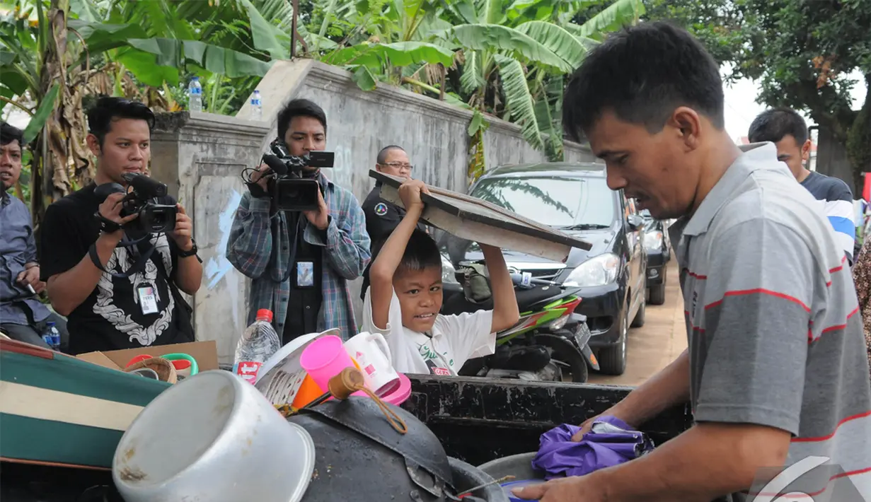 Sony Wakwaw bersama ayahnya mengangkat beberapa barang saat pindah rumah di kawasan Cibubur, Jakarta Timur. Foto diambil pada Kamis (4/12/2014). (Liputan6.com/Herman Zakharia)