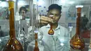 Seorang pengunjung mengamati sebuah gelas labu laboratorium dalam Pameran Farmasi Asia di Dhaka, Bangladesh, Jumat (28/2/2020). Pameran yang berfokus pada produk dan layanan medis serta teknologi farmasi ini berlangsung pada28 Februari hingga 1 Maret 2020. (Xinhua/Str)